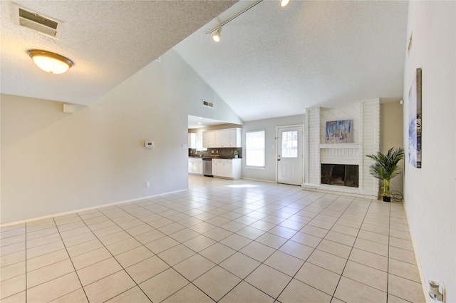 unfurnished living room featuring a textured ceiling, track lighting, light tile patterned floors, and a fireplace