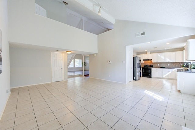 unfurnished living room with high vaulted ceiling, beam ceiling, sink, and light tile patterned flooring