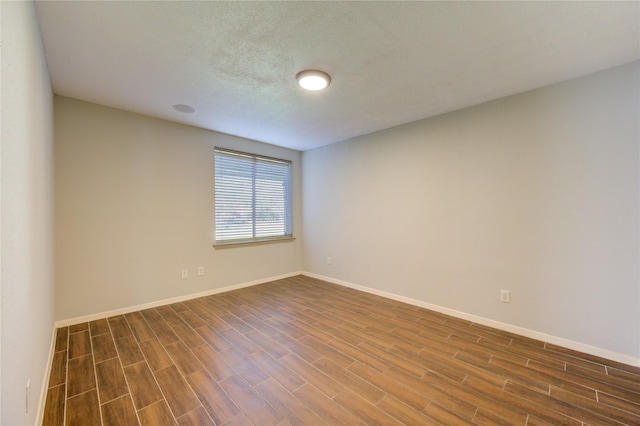 empty room with dark hardwood / wood-style flooring and a textured ceiling