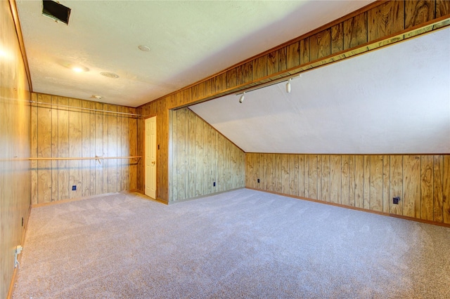 bonus room with light carpet, vaulted ceiling, and wooden walls