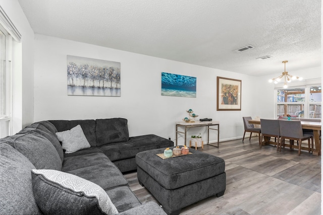 living room featuring a textured ceiling, hardwood / wood-style floors, and an inviting chandelier