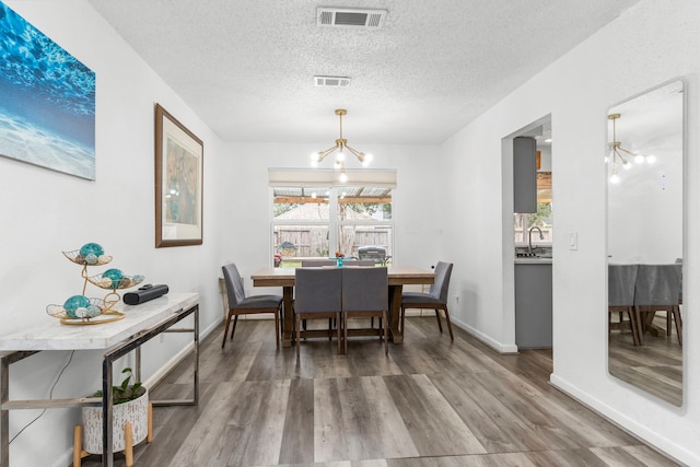 dining area featuring a notable chandelier, hardwood / wood-style floors, and a textured ceiling