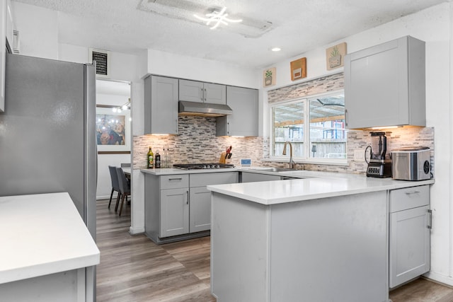 kitchen with kitchen peninsula, a textured ceiling, stainless steel appliances, gray cabinets, and sink