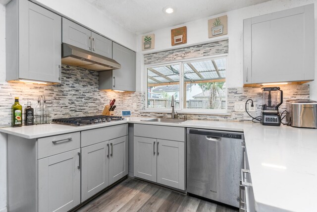 kitchen with stainless steel appliances, sink, hardwood / wood-style flooring, tasteful backsplash, and gray cabinets