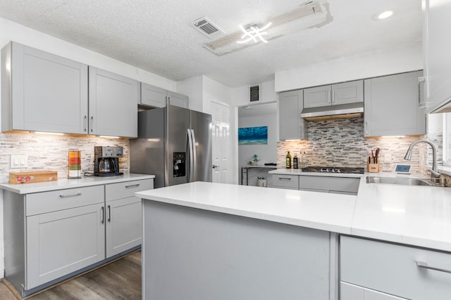 kitchen with a textured ceiling, stainless steel appliances, gray cabinets, backsplash, and sink