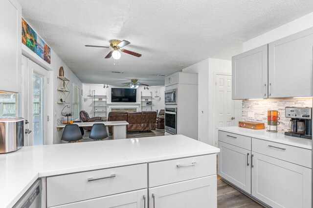 kitchen with stainless steel appliances, decorative backsplash, a textured ceiling, and white cabinetry