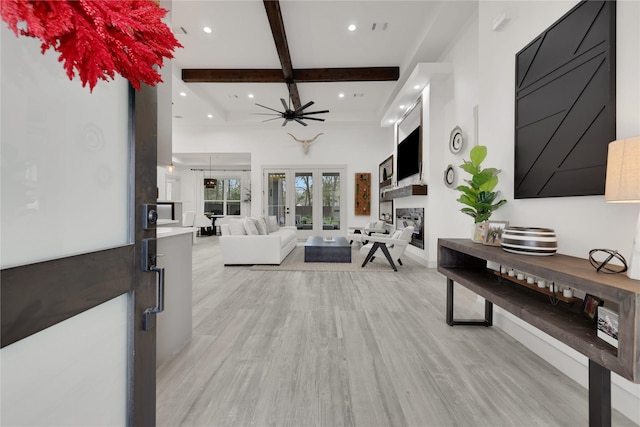 living room featuring light wood-type flooring, ceiling fan, and beam ceiling