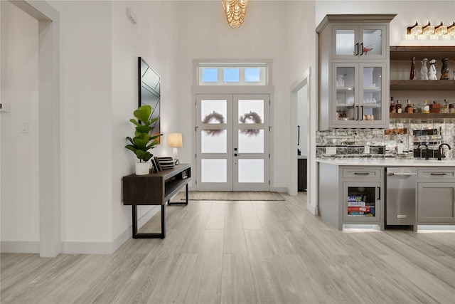 foyer entrance featuring a high ceiling, french doors, and light hardwood / wood-style flooring