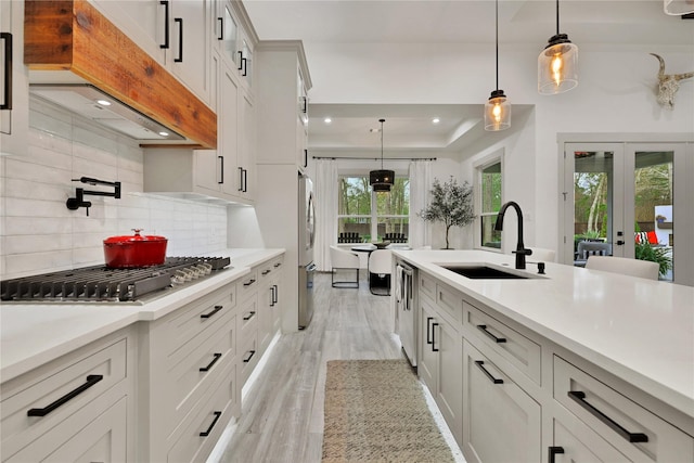 kitchen featuring pendant lighting, french doors, tasteful backsplash, appliances with stainless steel finishes, and sink