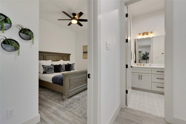 bedroom with sink, light hardwood / wood-style floors, connected bathroom, and ceiling fan