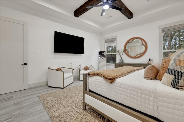 bedroom with ceiling fan, light wood-type flooring, multiple windows, and beam ceiling