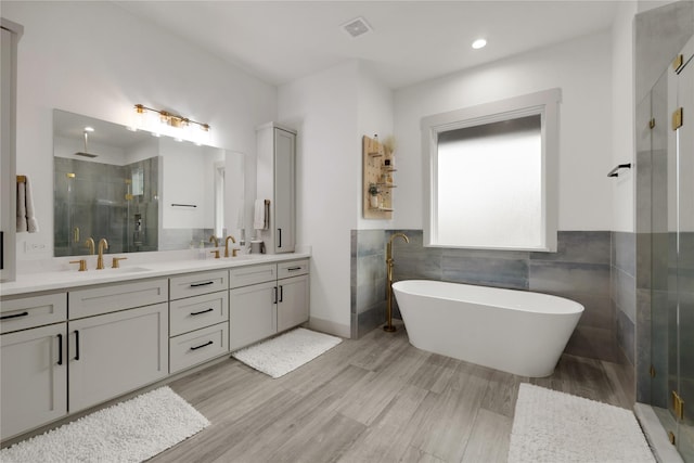 bathroom with hardwood / wood-style flooring, plus walk in shower, and vanity