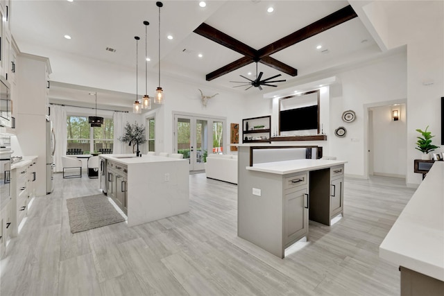 kitchen with pendant lighting, french doors, a large island with sink, ceiling fan, and beamed ceiling