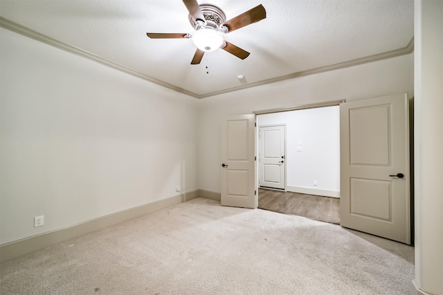 unfurnished bedroom featuring ceiling fan, light colored carpet, and crown molding