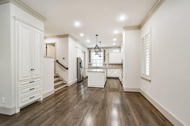 kitchen featuring dark wood-type flooring, a center island, decorative light fixtures, white cabinetry, and sink