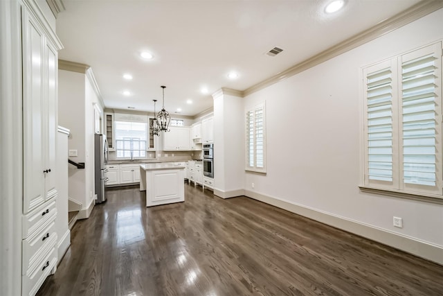 kitchen with stainless steel appliances, a center island, dark wood-type flooring, white cabinetry, and decorative light fixtures