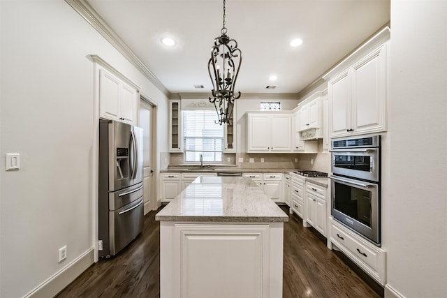 kitchen featuring stainless steel appliances, a center island, light stone countertops, white cabinetry, and decorative light fixtures