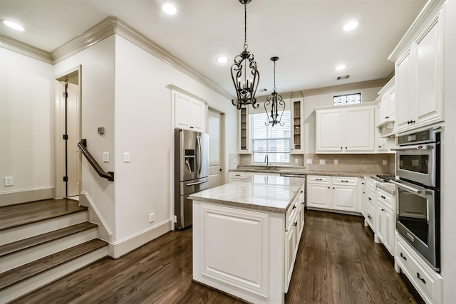 kitchen featuring white cabinets, a center island, hanging light fixtures, light stone countertops, and appliances with stainless steel finishes