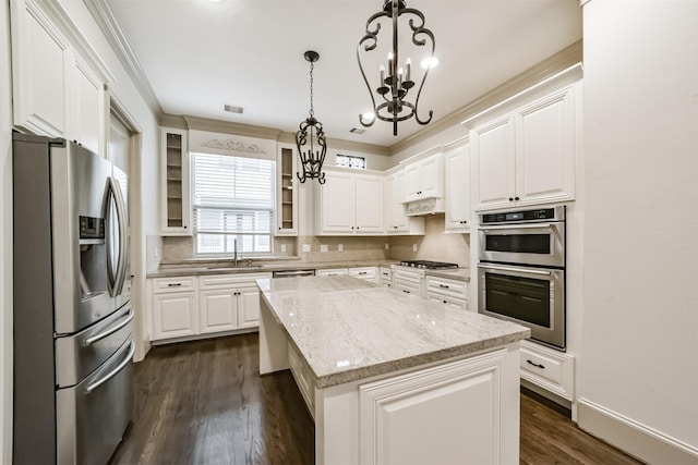 kitchen with white cabinetry, hanging light fixtures, light stone countertops, a kitchen island, and appliances with stainless steel finishes