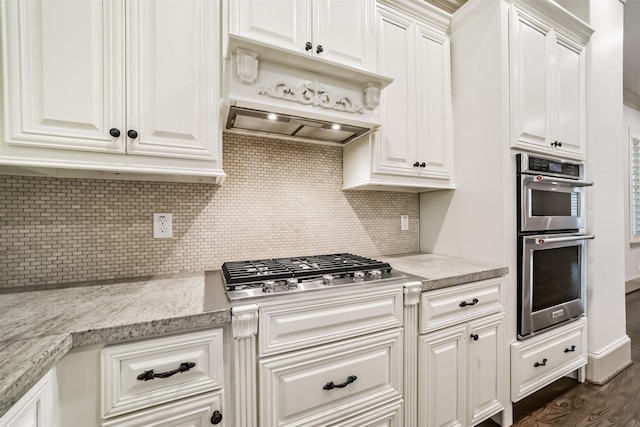 kitchen with appliances with stainless steel finishes, light stone countertops, dark wood-type flooring, decorative backsplash, and white cabinetry