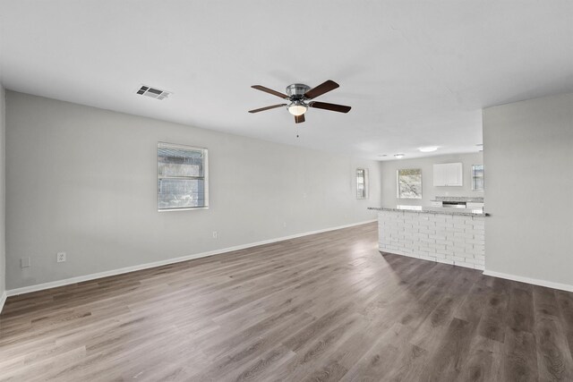 unfurnished living room featuring ceiling fan and hardwood / wood-style flooring