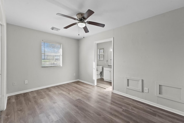 unfurnished bedroom featuring ceiling fan, connected bathroom, wood finished floors, visible vents, and baseboards