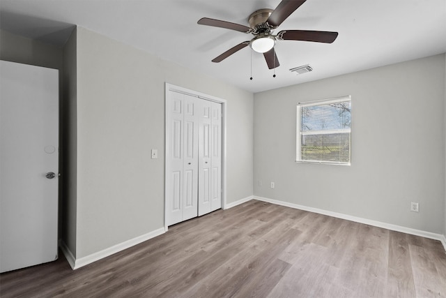 unfurnished bedroom with baseboards, a closet, visible vents, and light wood-style floors