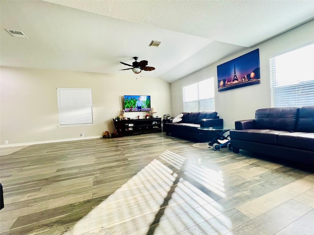 living room featuring lofted ceiling, hardwood / wood-style flooring, a textured ceiling, and ceiling fan