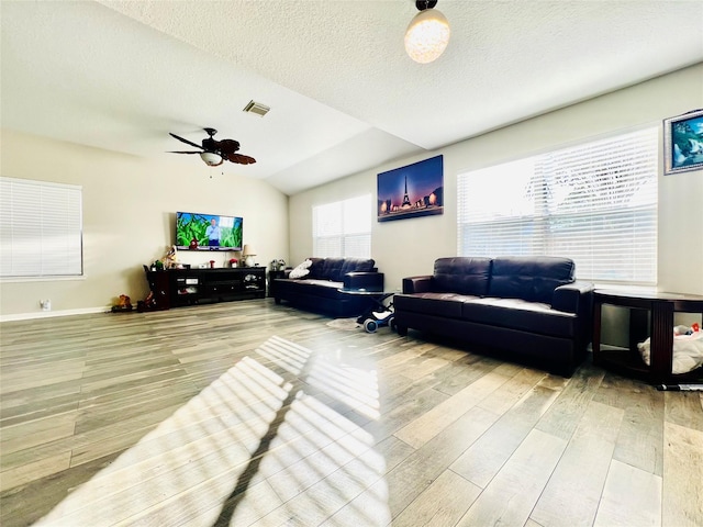 living room featuring vaulted ceiling, hardwood / wood-style flooring, a textured ceiling, and ceiling fan