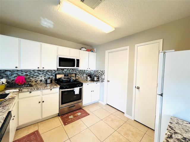 kitchen with light stone countertops, a textured ceiling, light tile patterned floors, white cabinetry, and appliances with stainless steel finishes