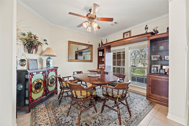 tiled dining area featuring ceiling fan and crown molding