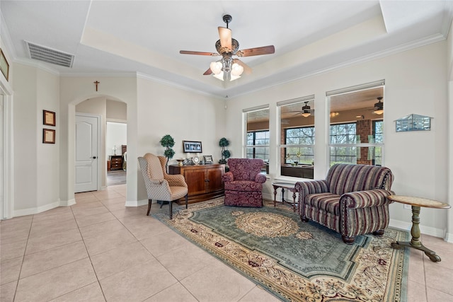 living room featuring a raised ceiling, light tile patterned floors, and crown molding