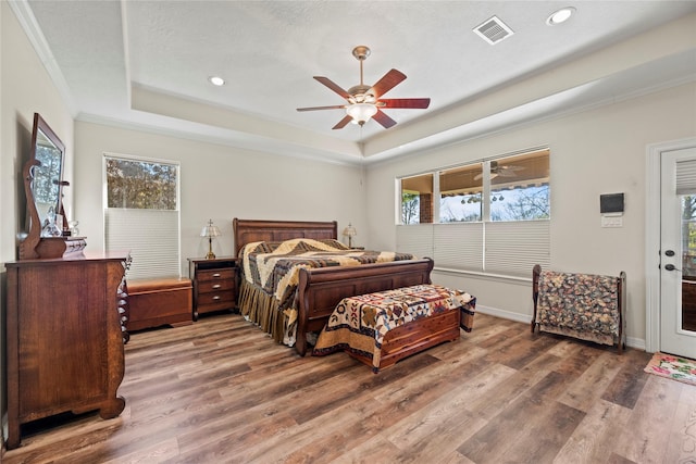 bedroom with wood-type flooring, a tray ceiling, ceiling fan, ornamental molding, and access to exterior