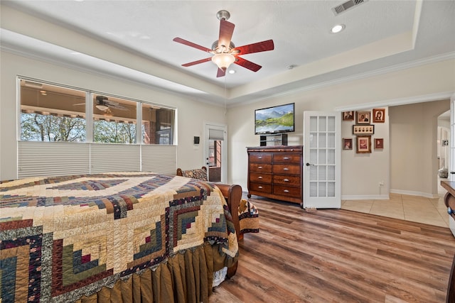 bedroom with french doors, ceiling fan, a tray ceiling, and wood-type flooring