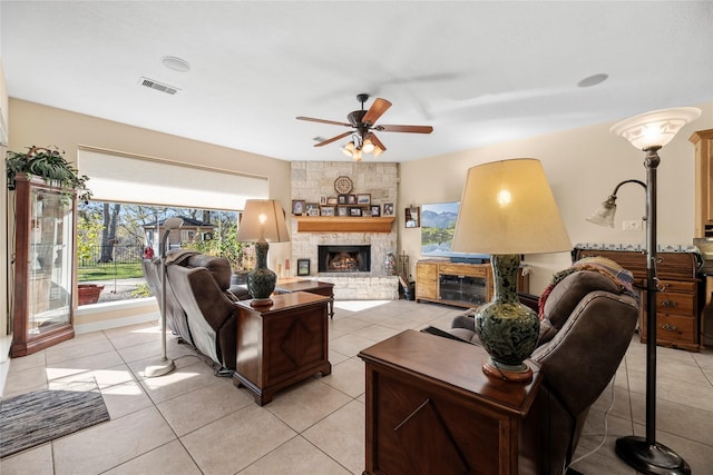 tiled living room featuring ceiling fan and a stone fireplace