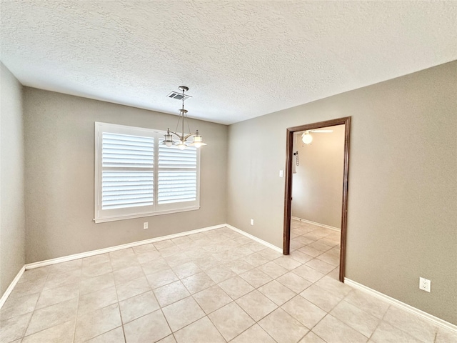 empty room with a textured ceiling, an inviting chandelier, and light tile patterned floors