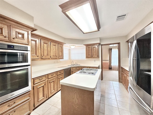 kitchen featuring sink, a center island, light tile patterned floors, plenty of natural light, and appliances with stainless steel finishes