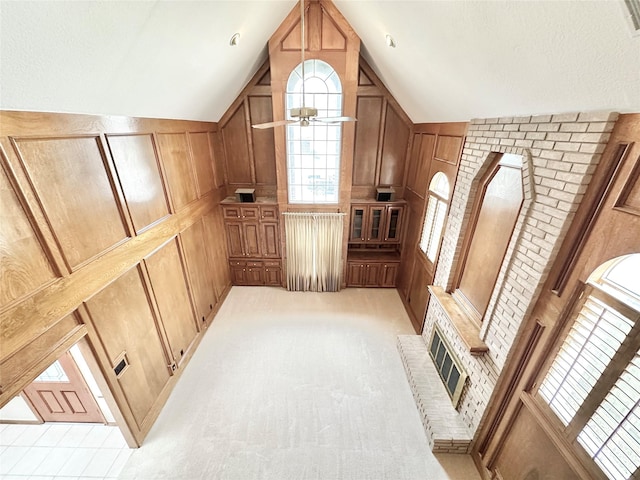 bonus room featuring lofted ceiling, ceiling fan, wooden walls, and light carpet