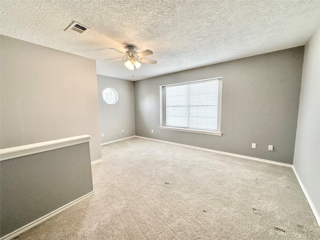 carpeted spare room with a textured ceiling and ceiling fan