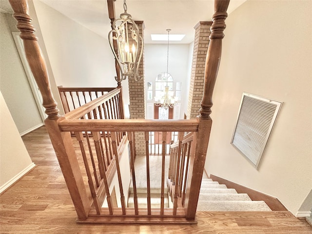 staircase with wood-type flooring and a chandelier