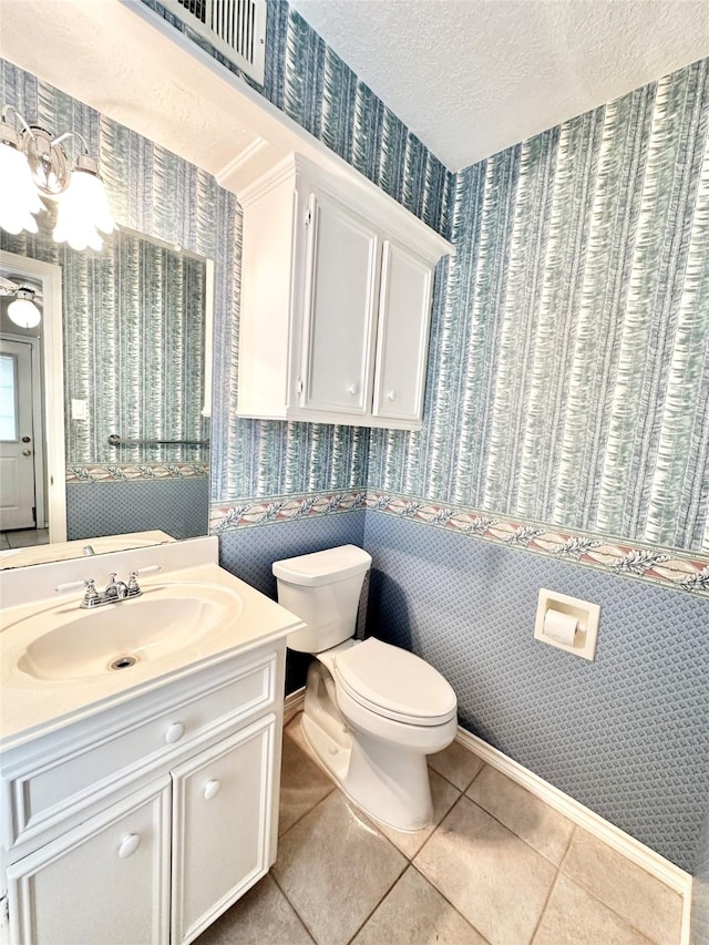 bathroom with a textured ceiling, tile patterned flooring, vanity, and toilet