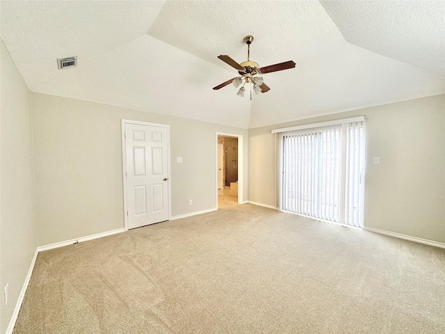 interior space featuring ceiling fan, vaulted ceiling, light carpet, and a textured ceiling