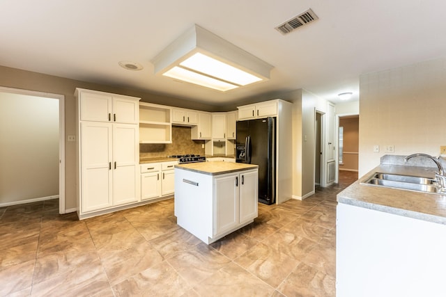 kitchen with sink, white cabinets, and black fridge with ice dispenser