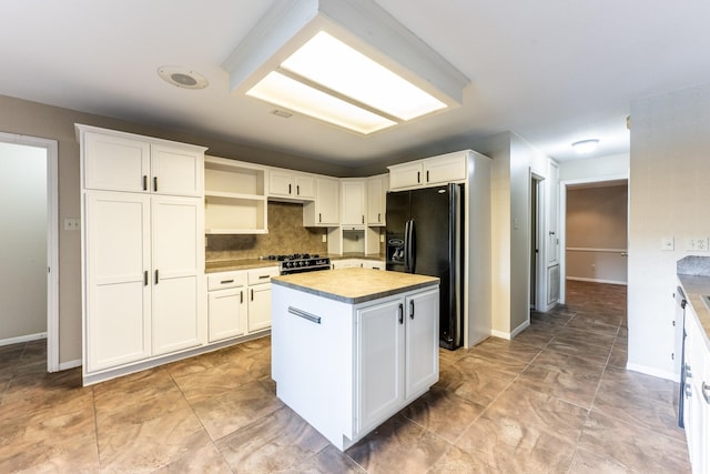 kitchen with a kitchen island, white cabinets, backsplash, and black appliances