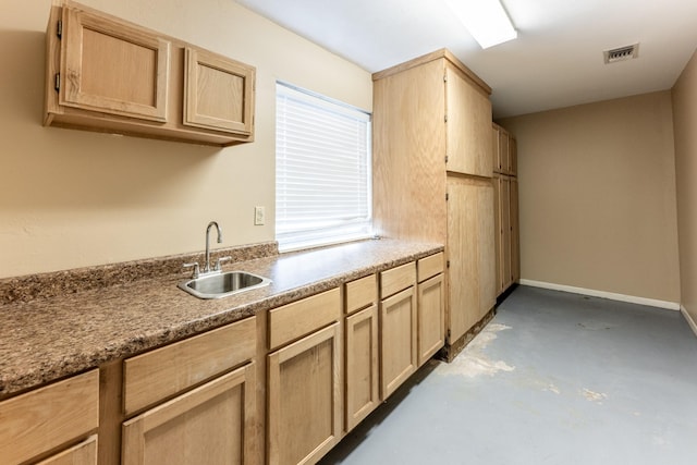 kitchen with concrete flooring, light brown cabinets, and sink