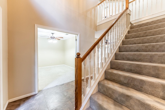 stairway with ceiling fan, carpet floors, and a high ceiling