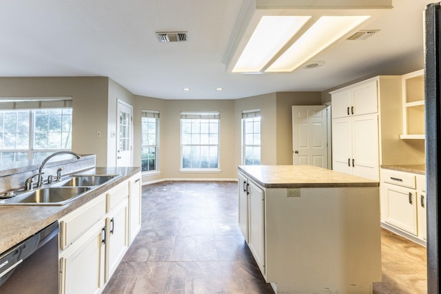 kitchen featuring a kitchen island, white cabinetry, black dishwasher, and sink