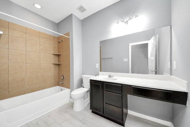 full bathroom featuring toilet, tiled shower / bath, and vanity