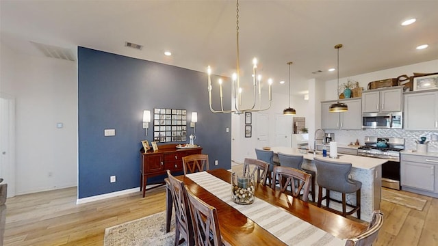 dining space featuring sink, light hardwood / wood-style flooring, and a chandelier