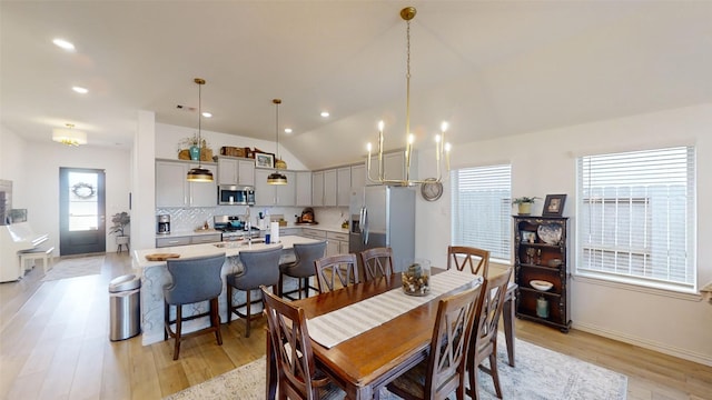 dining space with vaulted ceiling, light hardwood / wood-style floors, and a chandelier